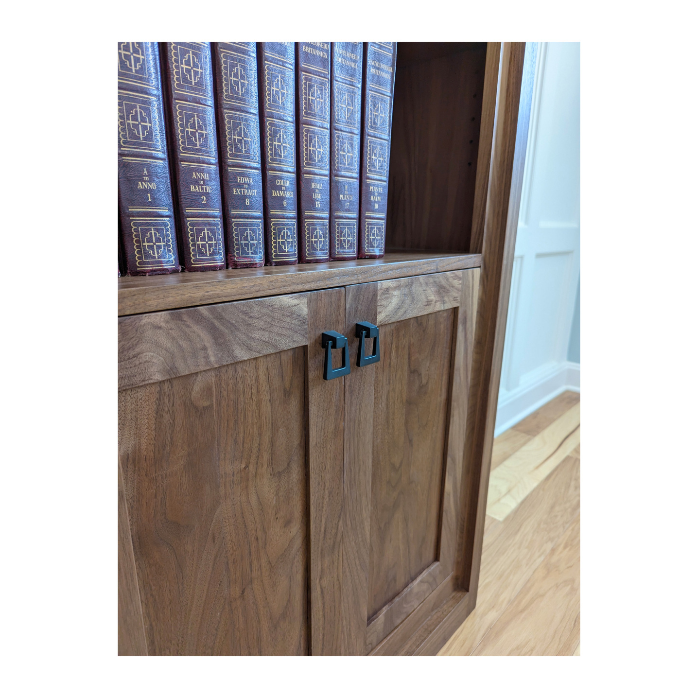 Solid wood doors with black matte handles on a bookcase