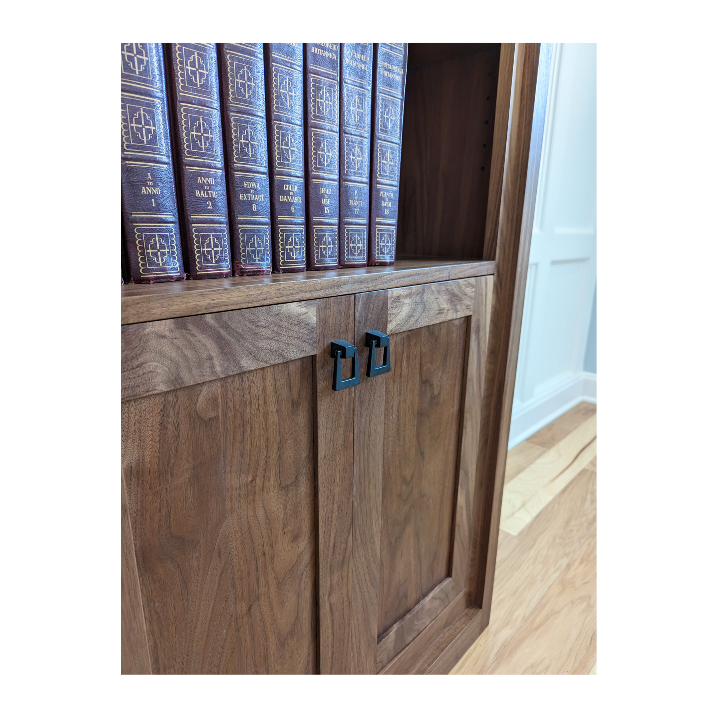 Solid wood doors with black matte handles on a bookcase